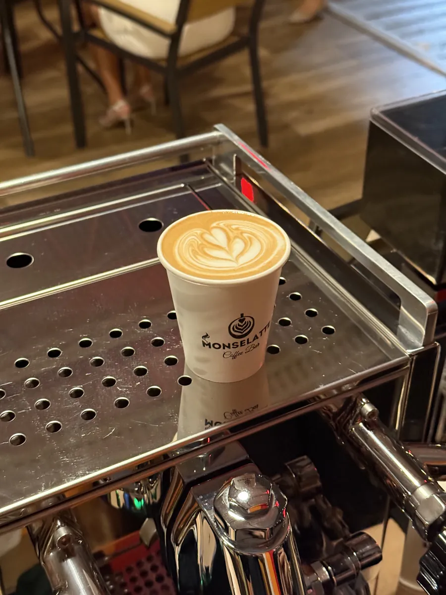 Bebida con latte art sobre la bandeja de una máquina de café