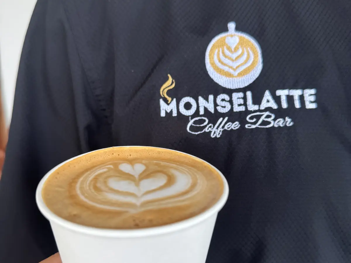 Vaso con latte art frente al uniforme de Monselatte