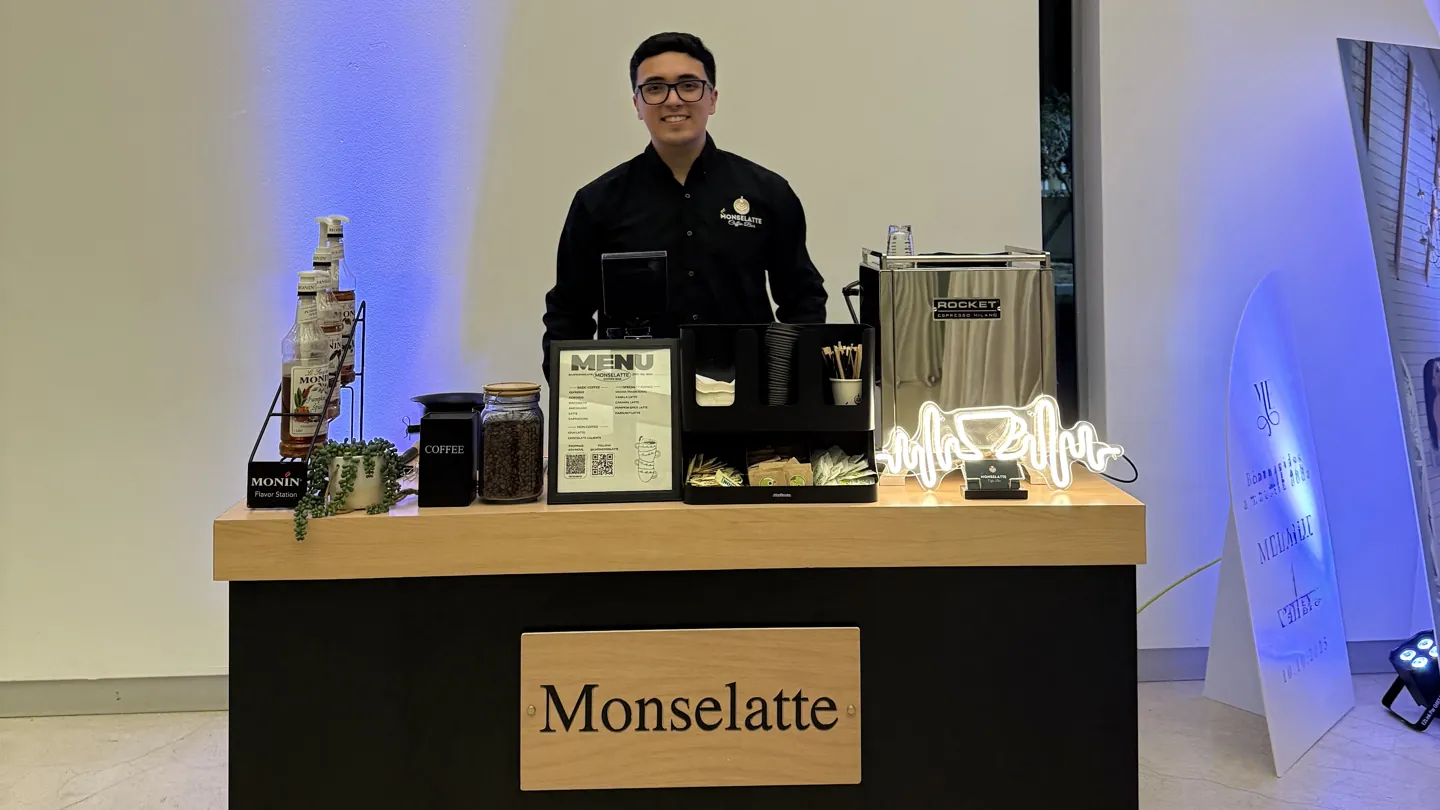 Barista de Monselatte detrás de la barra con iluminación azul al fondo